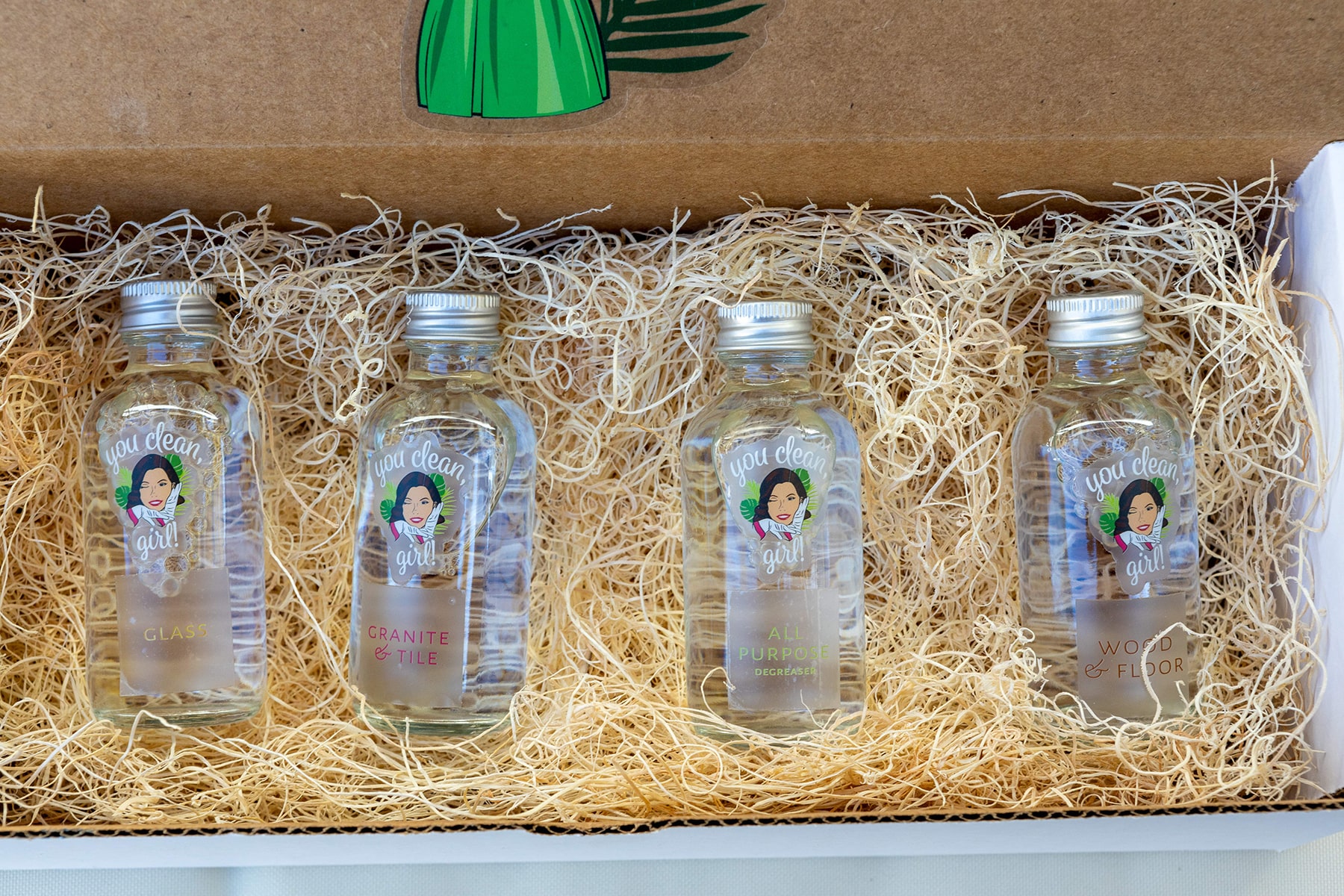 Four glass bottles lying on a heap of hay inside a box