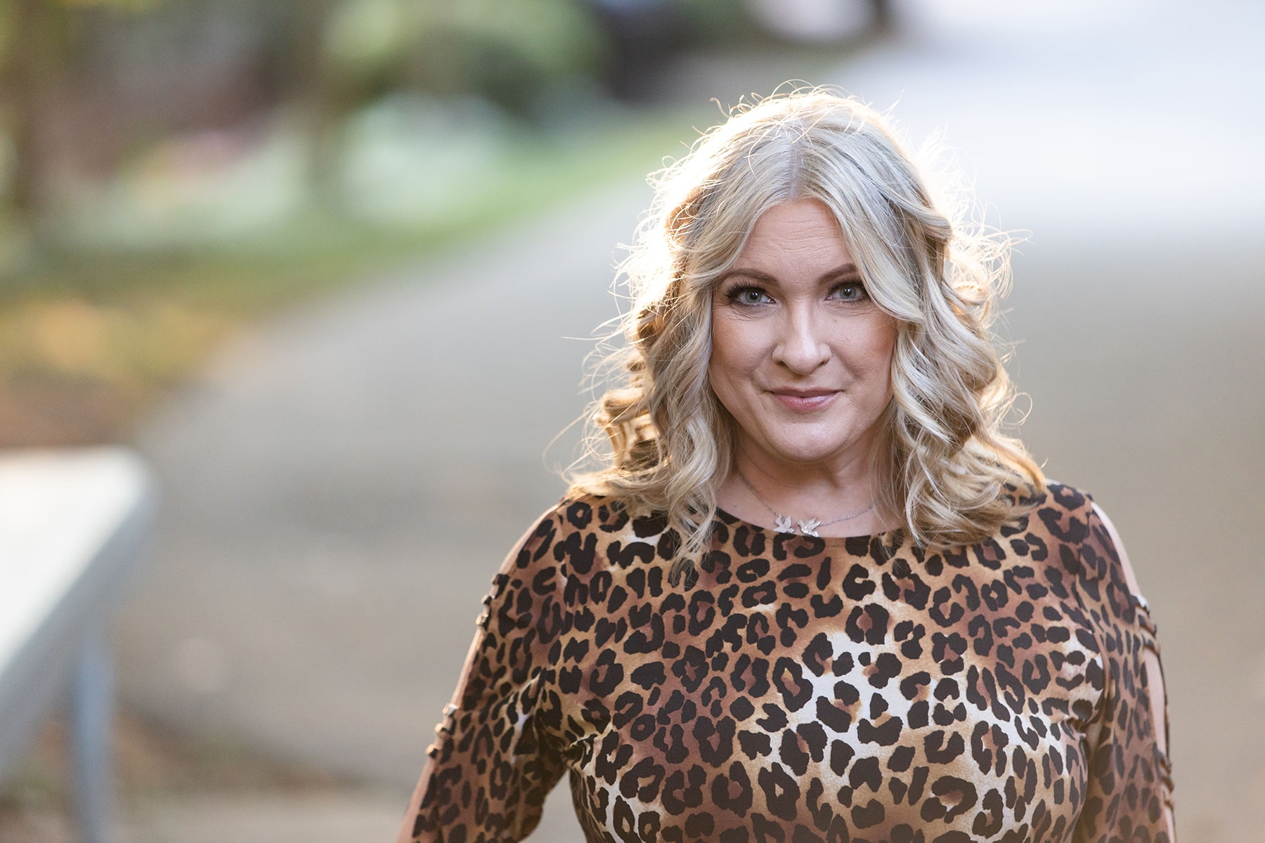 Blonde haired woman wearing a leopard print dress and smirking