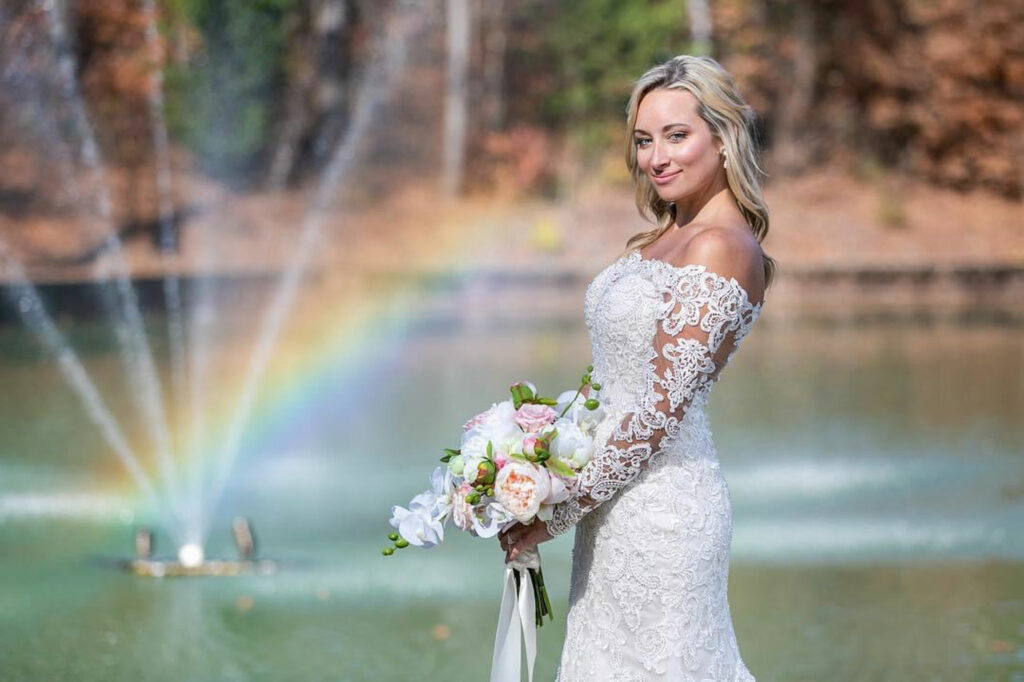Bride holding bouquet in front of fountain with rainbow | LaRuche Weddings